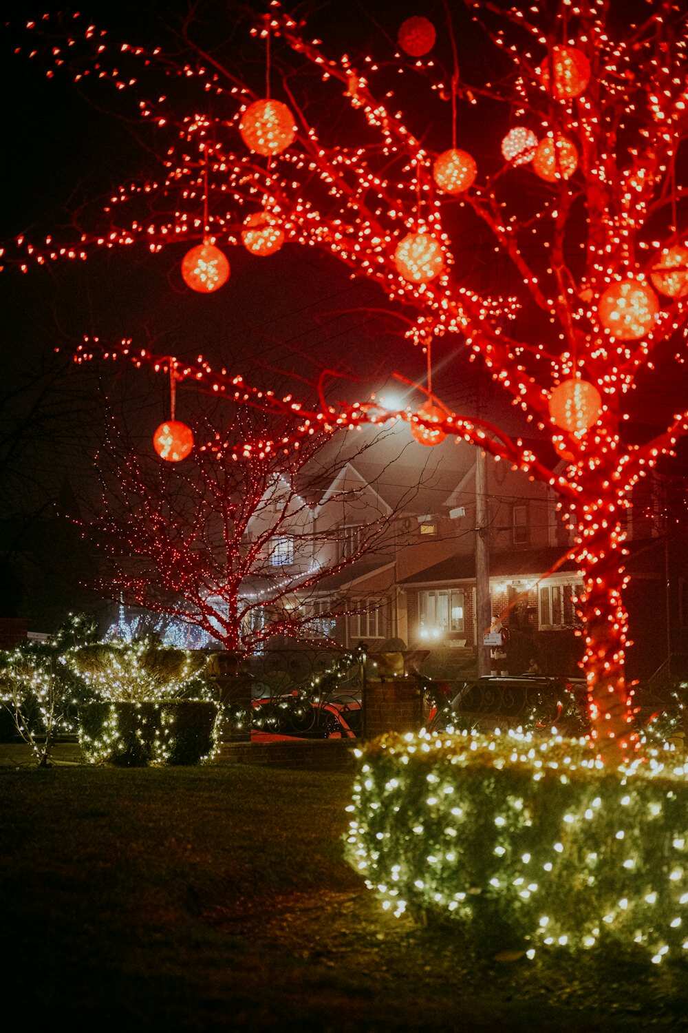 Tree wrapped in red Christmas lights with hanging ornament balls