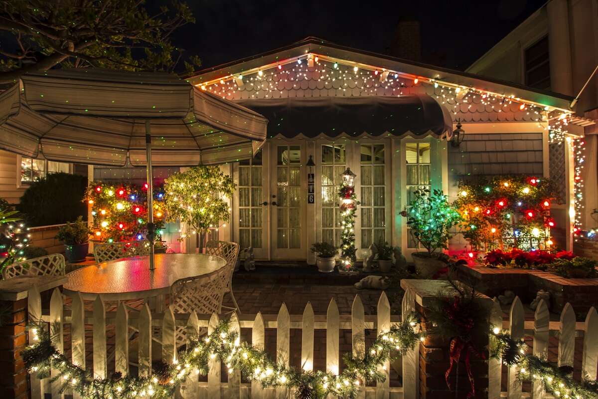 Patio and porch decorated with colorful Christmas lights and a covered umbrella at night